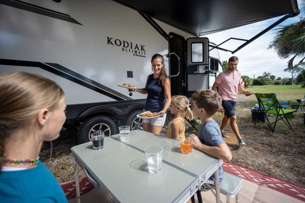 Kodiak RV with family having dinner outside